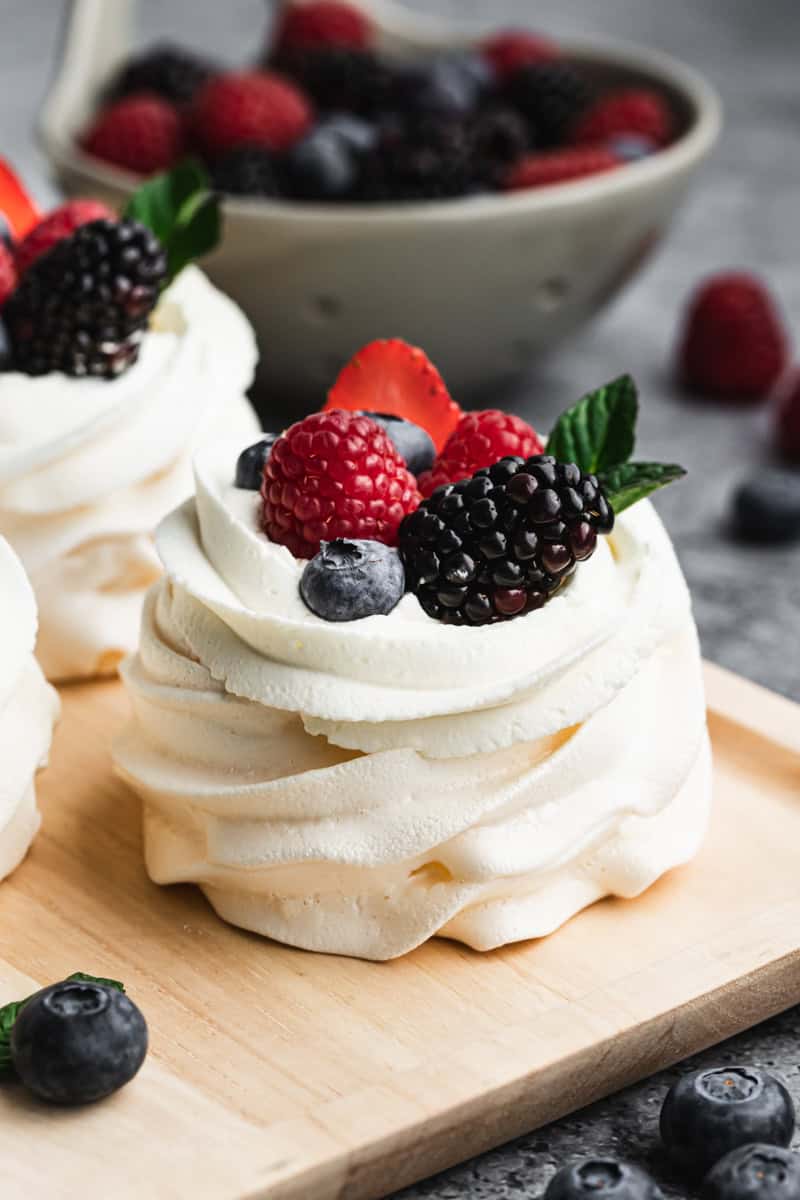 An easy Pavlova recipe made into individual mini pavlovas, topped with whipped crema and fresh berries. 