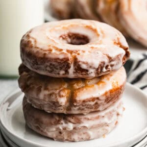 Three old fashioned sour cream donuts stacked on top of a plate, ready to enjoy.