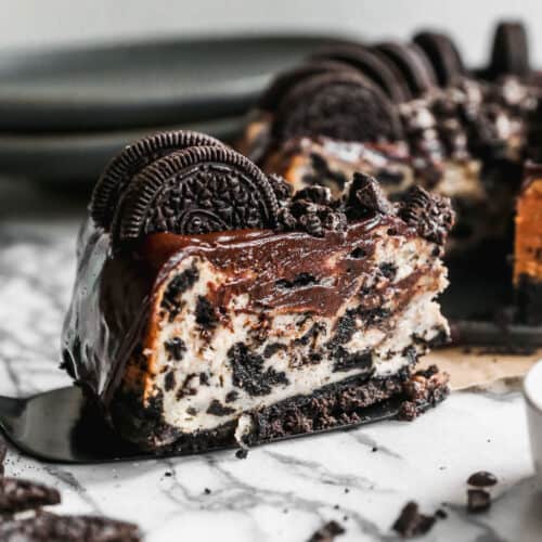 A slice of homemade Oreo Cheesecake on a pie spatula, ready to serve.