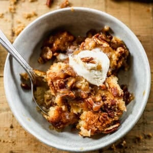 An easy Pecan Cobbler recipe in a bowl topped with vanilla ice cream.