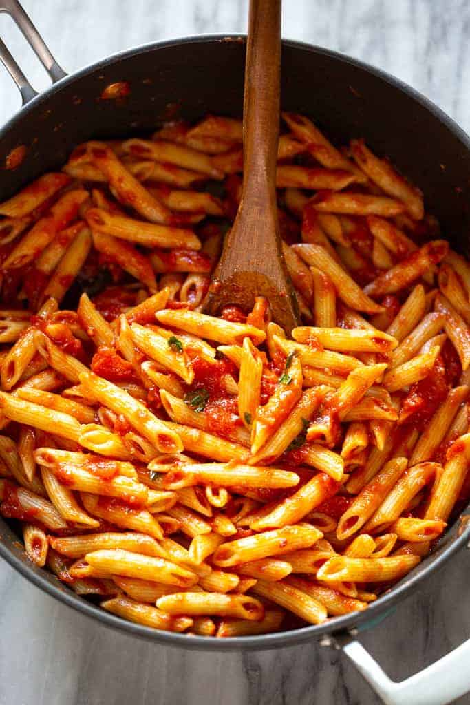 Penne pasta tossed in arrabbiata sauce in a skillet.