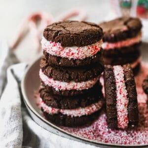 A stack of easy Peppermint Oreos with crushed candy canes around the edges of the frosting, ready to eat.