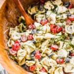 A wooden bowl filled with Pesto Tortellini salad, ready to serve.