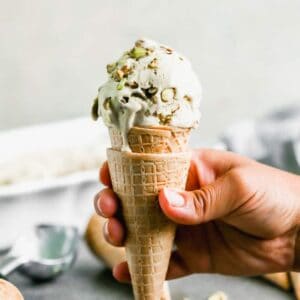 A waffle cone with a scoop of homemade pistachio ice cream in it.