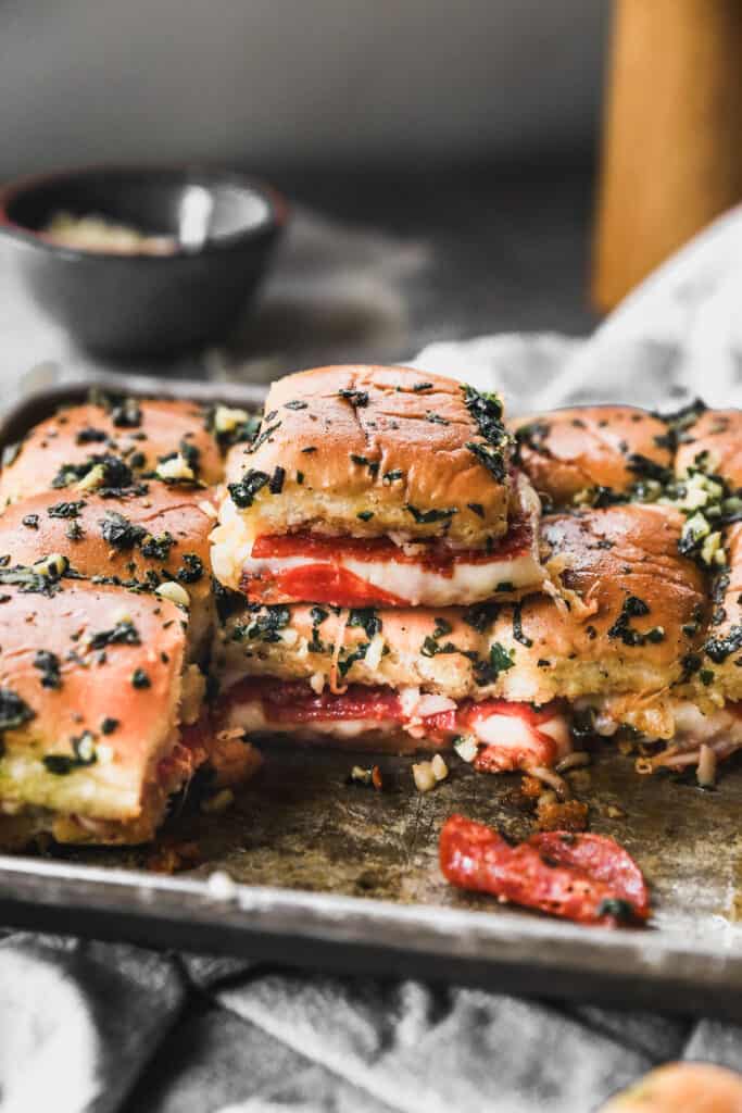 Two easy Pizza Sliders stacked on top of each other on a pan full of Pizza Sliders, ready to serve.