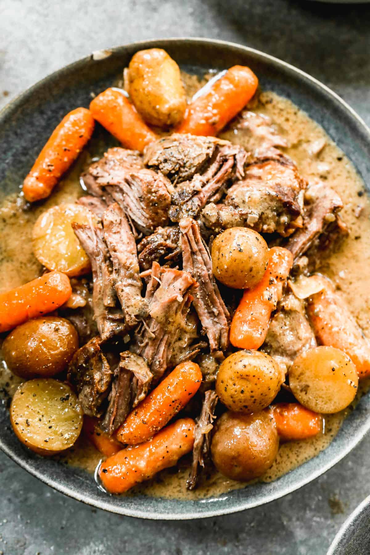 A slow cooker Pot Roast made from a chuck roast with potatoes and carrots on a serving platter, ready to enjoy.