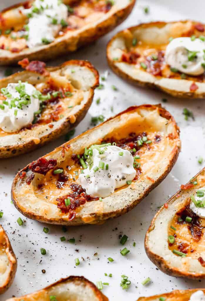 A loaded potato skin with cheese, bacon and a small scoop of sour cream on top.