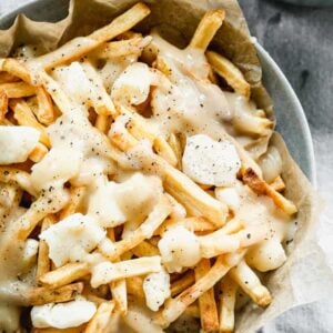 A bowl filled with Canadian Poutin, including fries topped with white cheese curd and gravy.