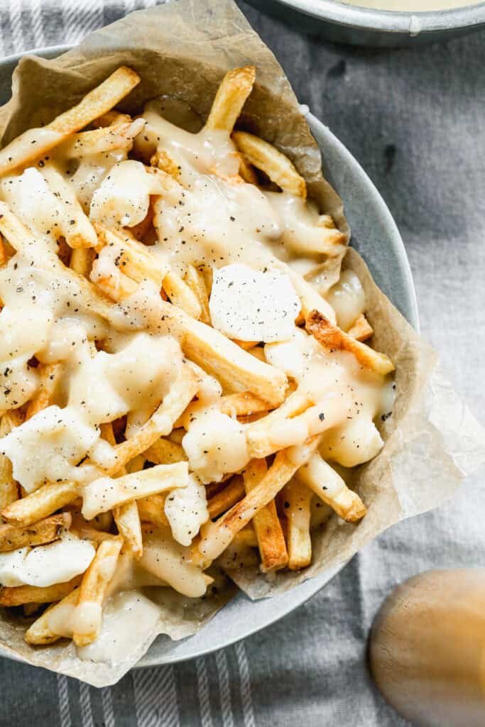 A Canadian poutine recipe in a bowl topped with cheese curds and brown gravy.