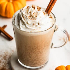 A glass of Pumpkin Spice Eggnog topped with whipped cream and a sprinkle of cinnamon.