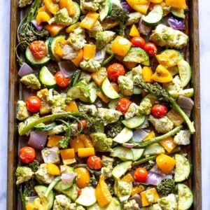 A sheet pan with pesto chicken and chopped vegetables.