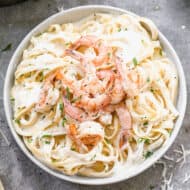 A bowl of homemade Shrimp Alfredo topped with chopped fresh parsley.