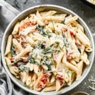 A bowl with sun dried tomato pasta and garnished with fresh basil.