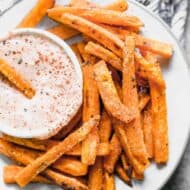 Sweet potato fries on a white plate with a side of fry sauce.