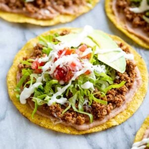 Tostada shells topped with refried beans, seasoned ground beef, lettuce, avocado, pico de gallo and sour cream.