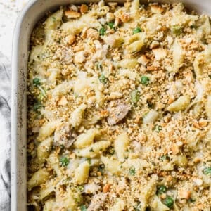 A 9x13 pan filled with an old fashioned tuna casserole recipe with shell pasta, peas, a creamy sauce, and topped with breadcrumbs.