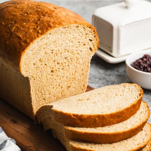 The best whole wheat bread recipe on a cutting board with four slices freshly cut and ready to enjoy with butter and jam.